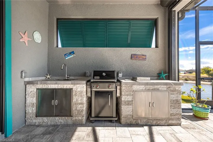 Outdoor grill/kitchen area with extra burner and sink with water.