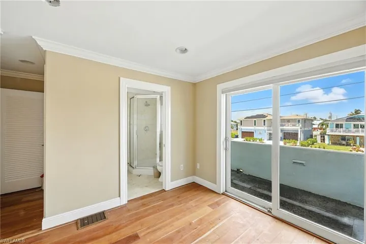 Empty room with light wood-style flooring, crown molding, and a residential view