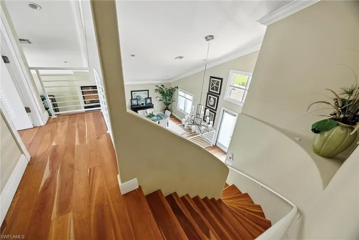 Staircase featuring wood finished floors and crown molding