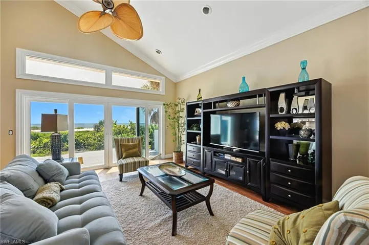 Living room featuring crown molding, high vaulted ceiling, wood finished floors, recessed lighting, and ceiling fan
