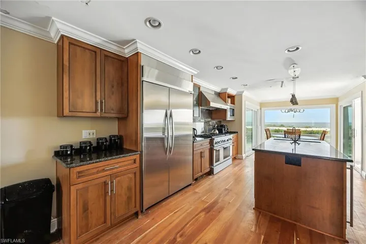 Kitchen featuring crown molding, stainless steel appliances, brown cabinets, light wood finished floors, and a kitchen island