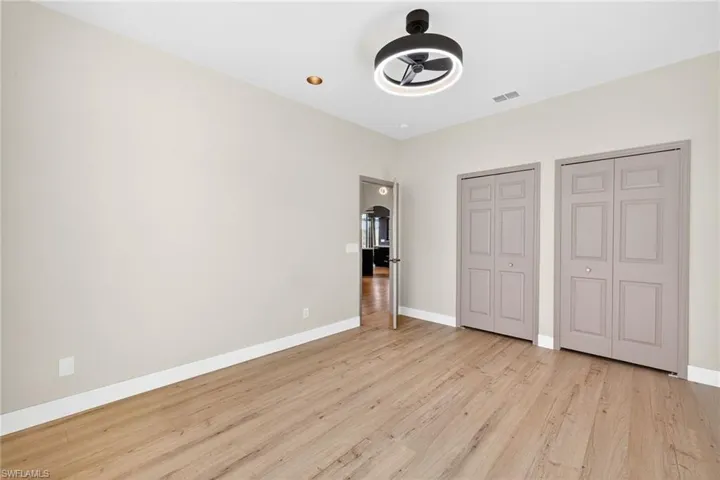 Unfurnished bedroom featuring multiple closets, light wood-style floors, and ceiling fan
