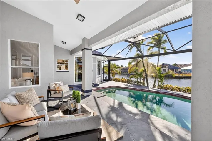 Outdoor pool featuring a sunroom, a patio area, a water view, glass enclosure, and outdoor seating