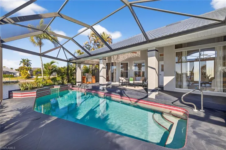 Relaxing pool / spa with glass enclosure, a sunroom, and a patio