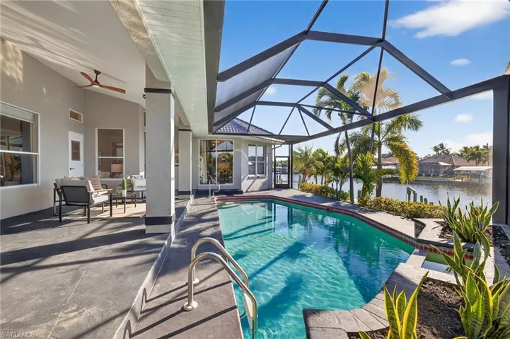 Outdoor pool featuring a sunroom, a patio, a water view, and glass enclosure