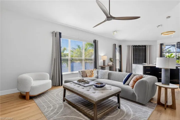 Living room with light wood-style flooring, a ceiling fan, healthy amount of natural light, and lofted ceiling