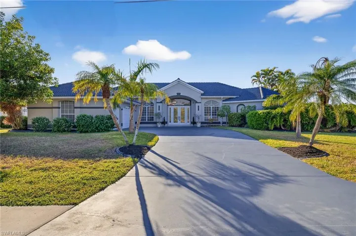 View of front of property with french doors, concrete driveway, a front yard, stucco siding, and a tile roof