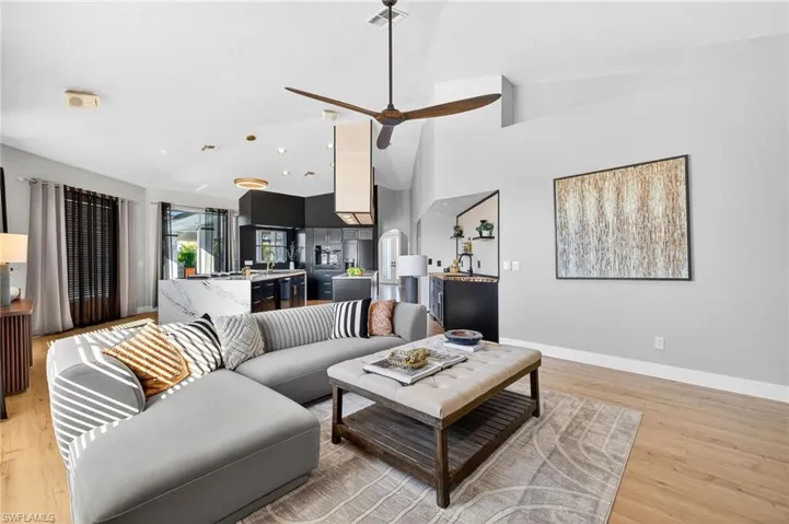 Living room with light wood-style floors, a ceiling fan, and lofted ceiling