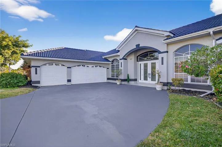 View of front of property with french doors, concrete driveway, a tiled roof, and stucco siding