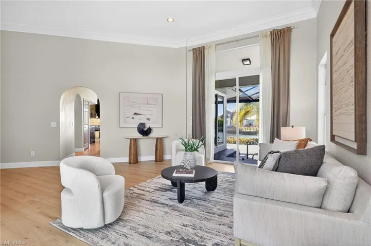 Sitting room with arched walkways, ornamental molding, wood finished floors, and recessed lighting