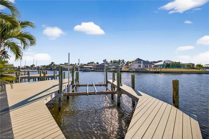 Dock with boat lift, a water view, and a residential view