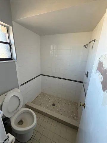 Full bath featuring a shower stall and light tile patterned flooring
