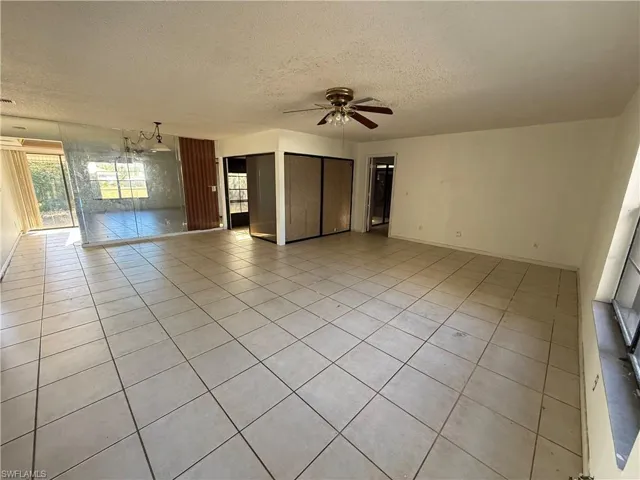 Unfurnished living room with a textured ceiling, light tile patterned flooring, and a ceiling fan