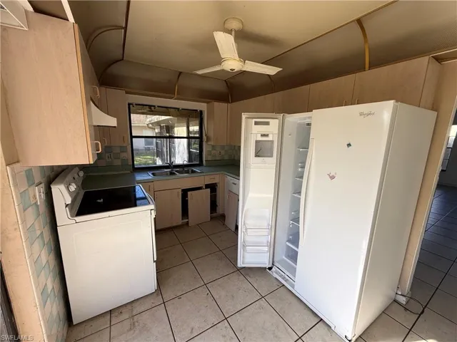 Kitchen featuring white appliances, washer / clothes dryer, ceiling fan, extractor fan, and light wood finish cabinetry