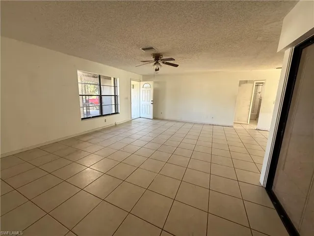 Unfurnished room featuring a textured ceiling, a ceiling fan, and light tile patterned floors