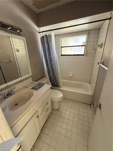 Bathroom featuring vanity and shower / bathtub combination with curtain