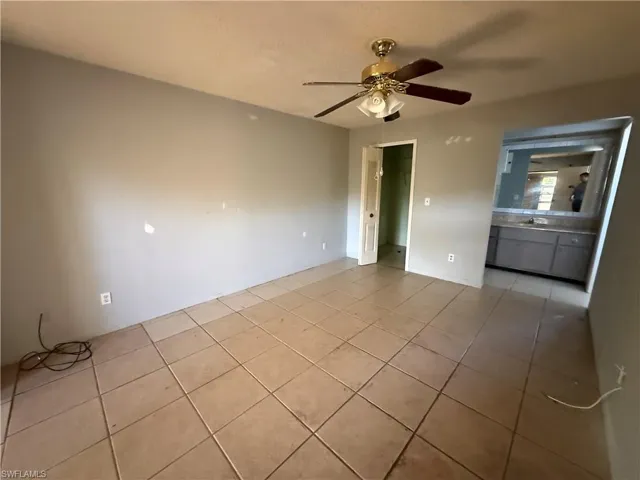 Unfurnished bedroom featuring light tile patterned floors, ceiling fan, and ensuite bath