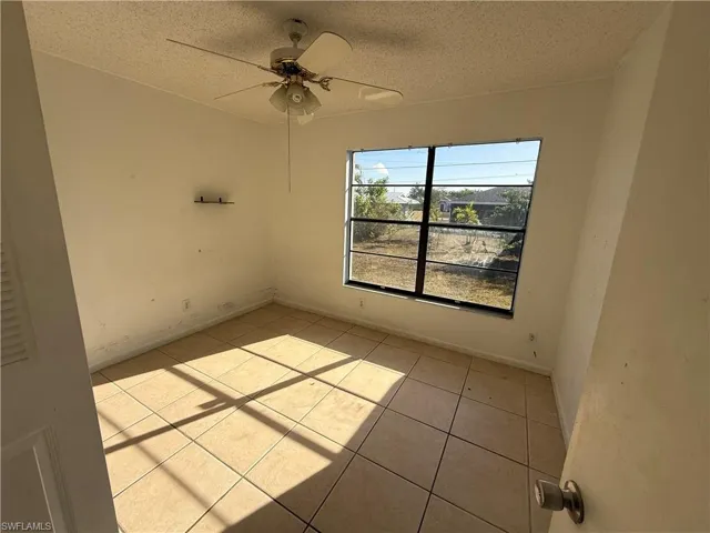Spare room with a textured ceiling, a ceiling fan, and light tile patterned floors