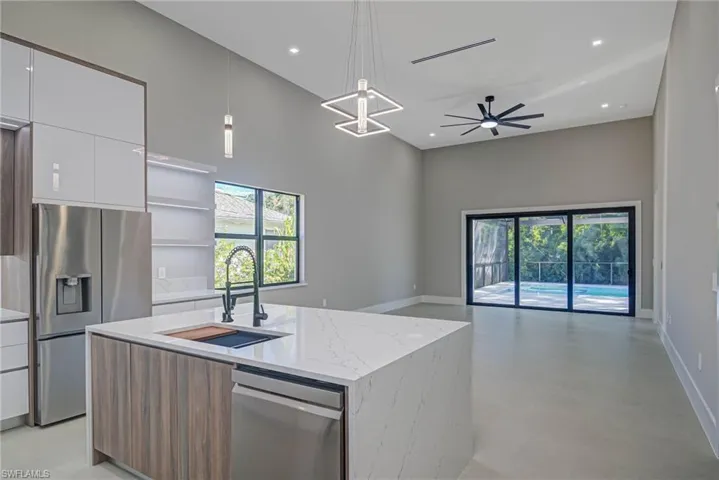 Kitchen with appliances with stainless steel finishes, pendant lighting, sink, white cabinets, and a kitchen island with sink