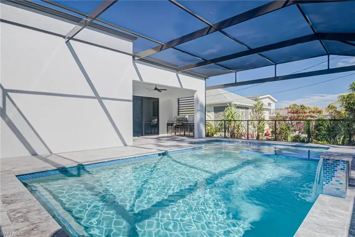View of swimming pool featuring a patio area, pool water feature, ceiling fan, and glass enclosure