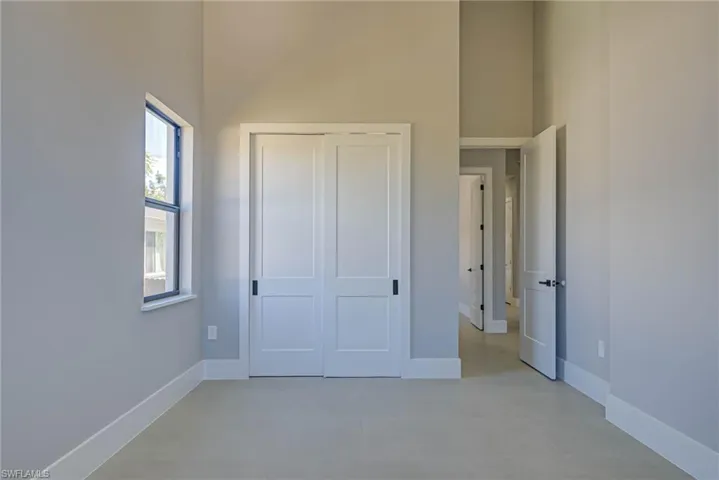 Unfurnished bedroom with a towering ceiling and a closet