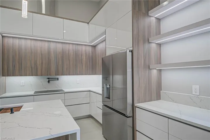 Kitchen featuring white cabinetry, light stone countertops, and stainless steel fridge with ice dispenser