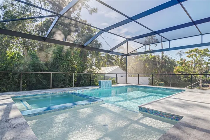 View of pool with a patio area, an in ground hot tub, and glass enclosure