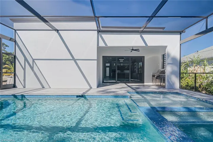 View of pool featuring a patio, ceiling fan, and glass enclosure