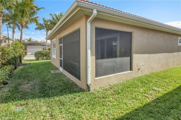View of property exterior featuring stucco siding, a lawn, and a sunroom
