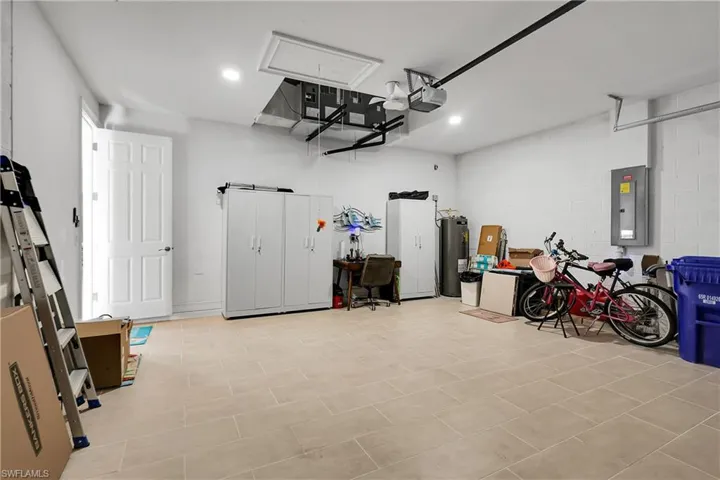 Garage featuring electric panel, water heater, and concrete block wall