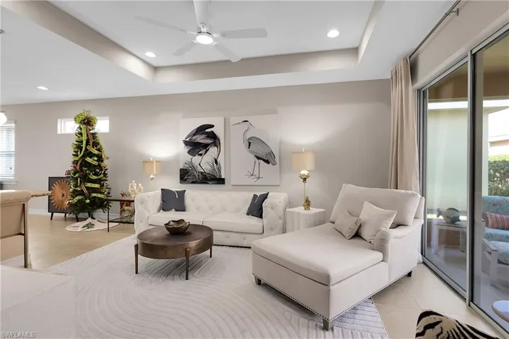 Living room with light tile patterned floors, a tray ceiling, recessed lighting, and a ceiling fan