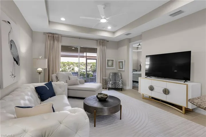 Living room featuring a ceiling fan, recessed lighting, and a raised ceiling