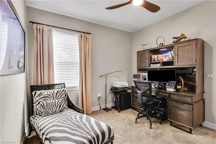 Bedroom featuring a desk, light colored carpet, and a ceiling fan