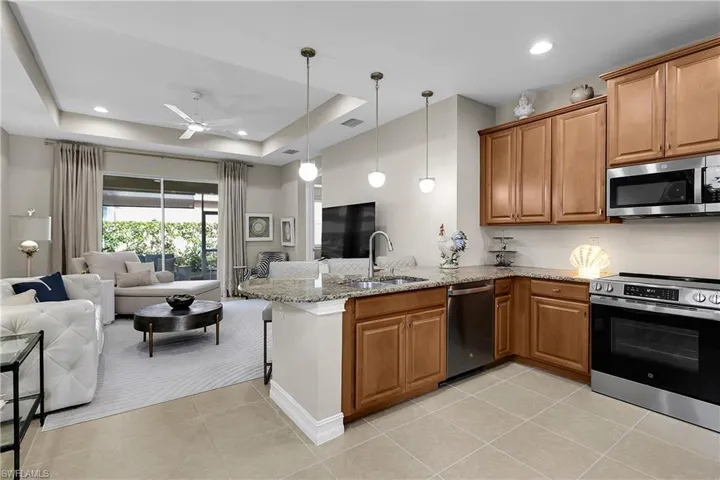 Kitchen with open floor plan, stainless steel appliances, brown cabinets, a peninsula, and recessed lighting