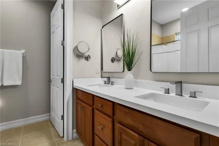 Bathroom with a shower with curtain, double vanity, and light tile patterned flooring