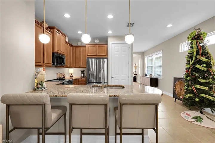 Kitchen featuring a peninsula, stainless steel appliances, a breakfast bar, decorative light fixtures, and recessed lighting