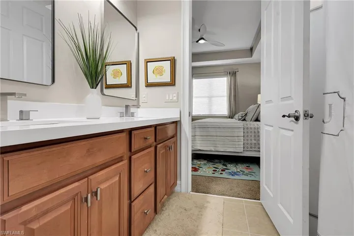 Full bath featuring double vanity, light tile patterned floors, ensuite bath, ceiling fan, and light carpet