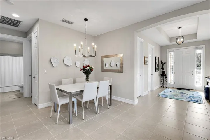 Dining area featuring a chandelier, a raised ceiling, light tile patterned flooring, and recessed lighting