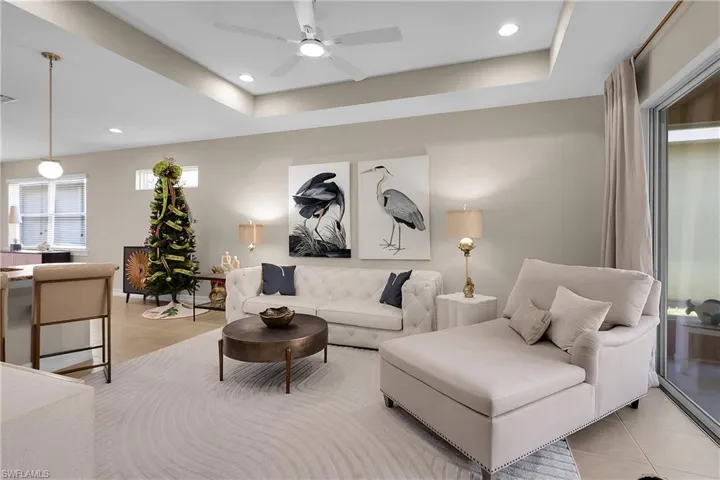 Living area with light tile patterned flooring, a tray ceiling, recessed lighting, and a ceiling fan