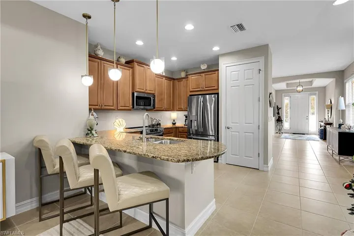 Kitchen featuring decorative light fixtures, a peninsula, a kitchen breakfast bar, recessed lighting, and light tile patterned floors