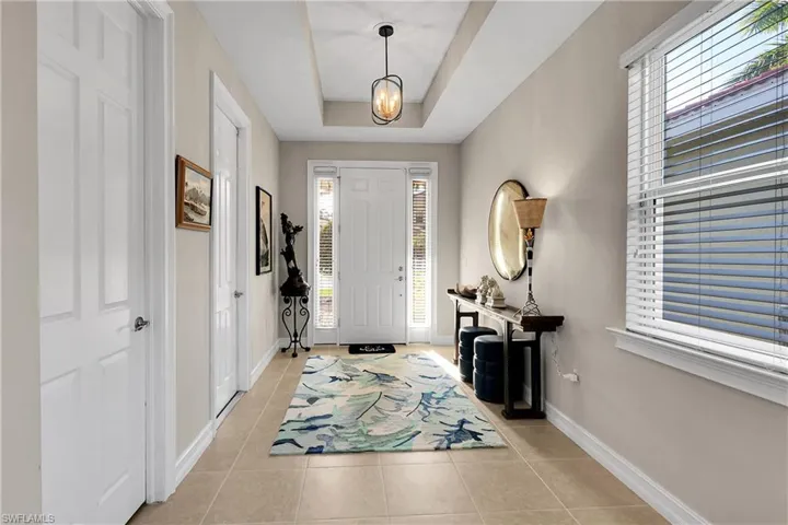 Entrance foyer featuring light tile patterned flooring, a raised ceiling, and a chandelier