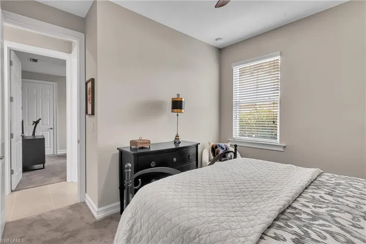 Bedroom with light carpet, ceiling fan, and light tile patterned floors