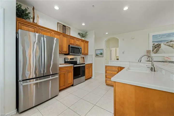 Kitchen with appliances with stainless steel finishes, light tile patterned floors, brown cabinetry, and light countertops