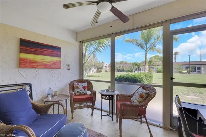 Screened lanai featuring textured walls, tile flooring, and a ceiling fan