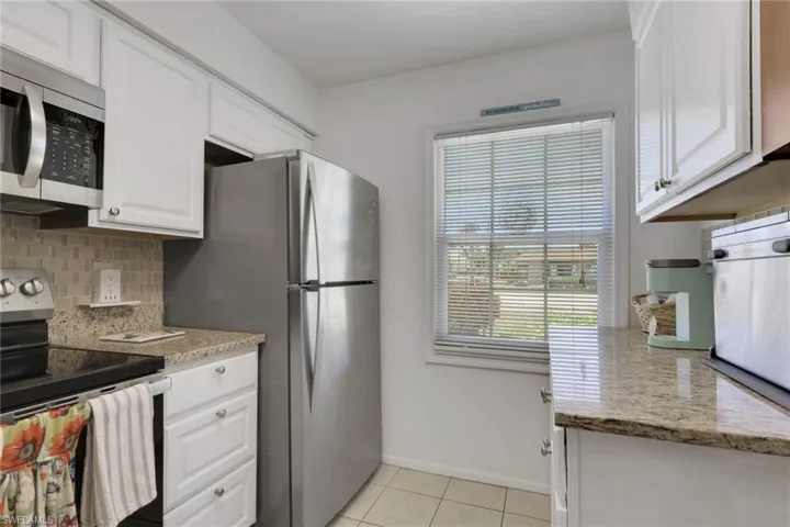 Kitchen featuring white cabinetry, granite-style countertops, stainless steel appliances, and a tiled backsplash