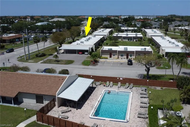 Community swimming pool area featuring a rectangular pool, surrounding patio, and covered lounge space