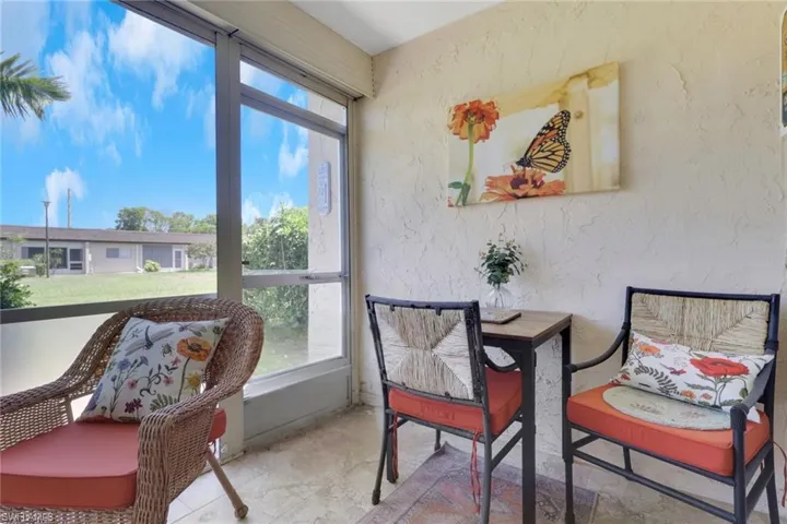 Screened lanai featuring large windows, stucco wall texture, and tile flooring