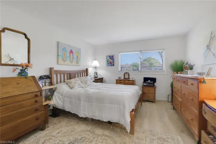 Bright bedroom featuring light wood-finish flooring, a generous window, and neutral wall tones