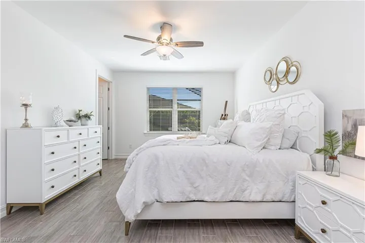 Primary Bedroom featuring ceiling fan and light wood-like tile flooring and walk in closet in the corner