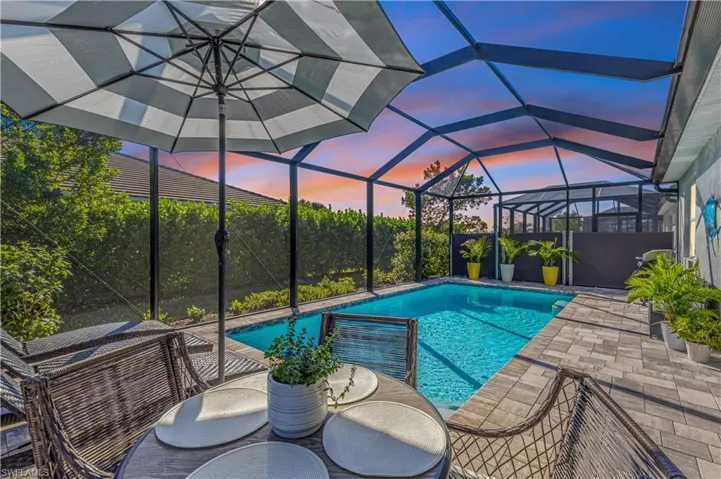 Pool under lanai with retractable privacy screens and sitting/lounging area